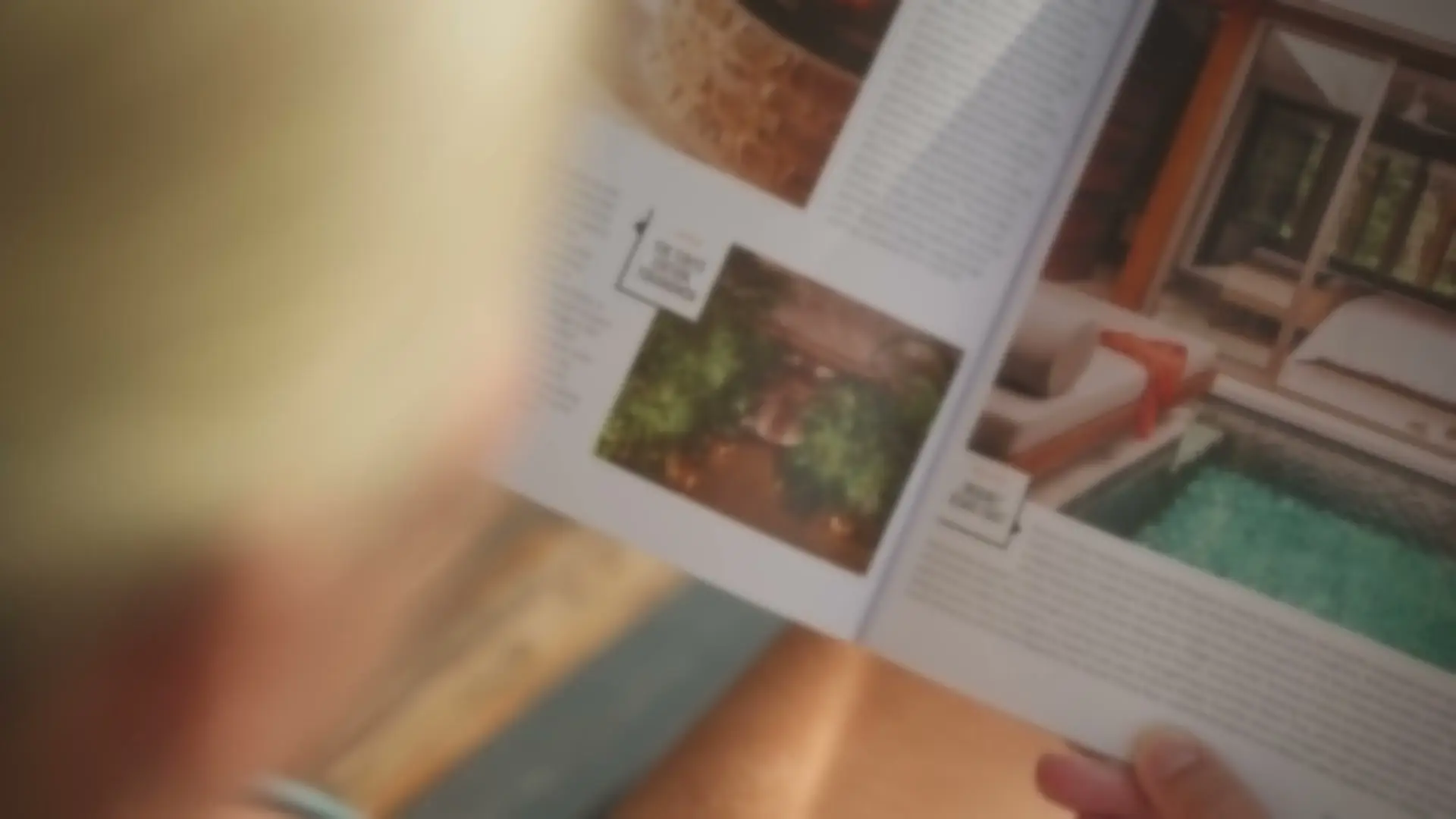 Mains qui tiennent un magazine ouvert sur une villa à piscine