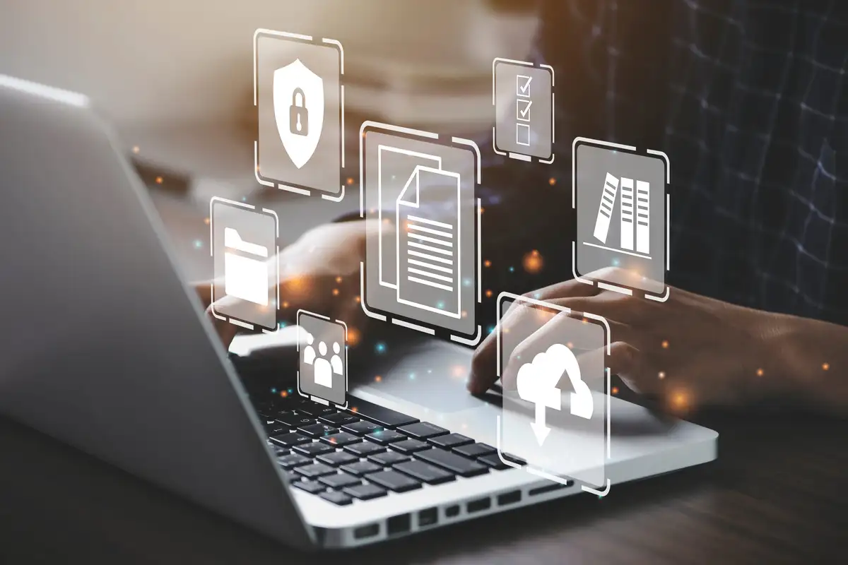 Des mains sur le clavier d’un ordinateur portable, entourées d’icônes de documents, de dossiers et d’un cadenas