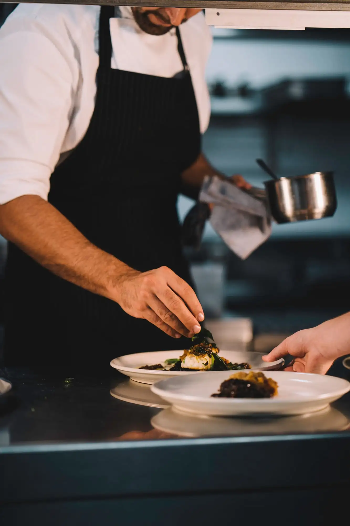 Chef en tablier dressant une assiette en cuisine