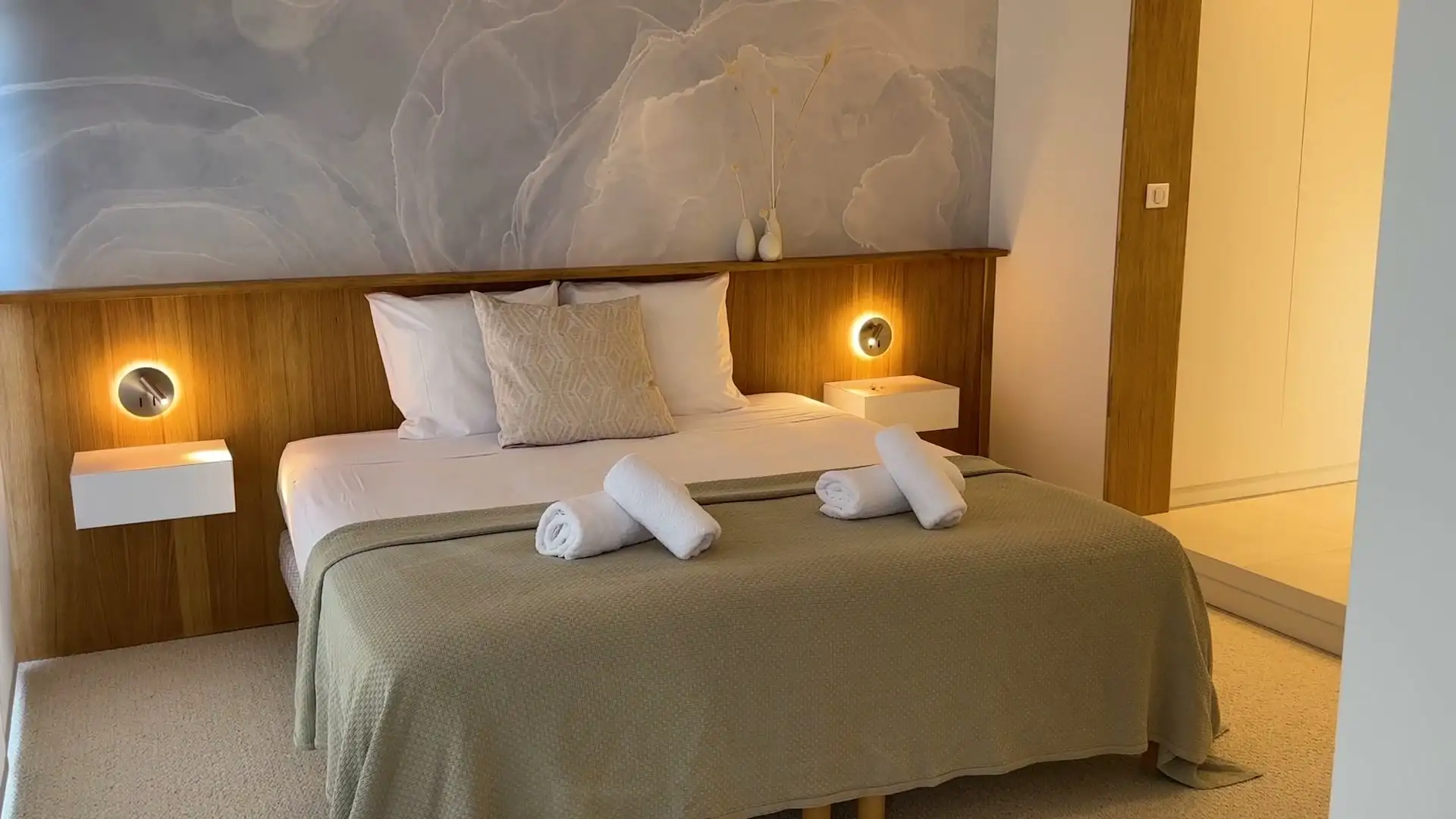 Chambre de la Villa Halo : lit fait, serviettes roulées, lampes de chevet allumées
