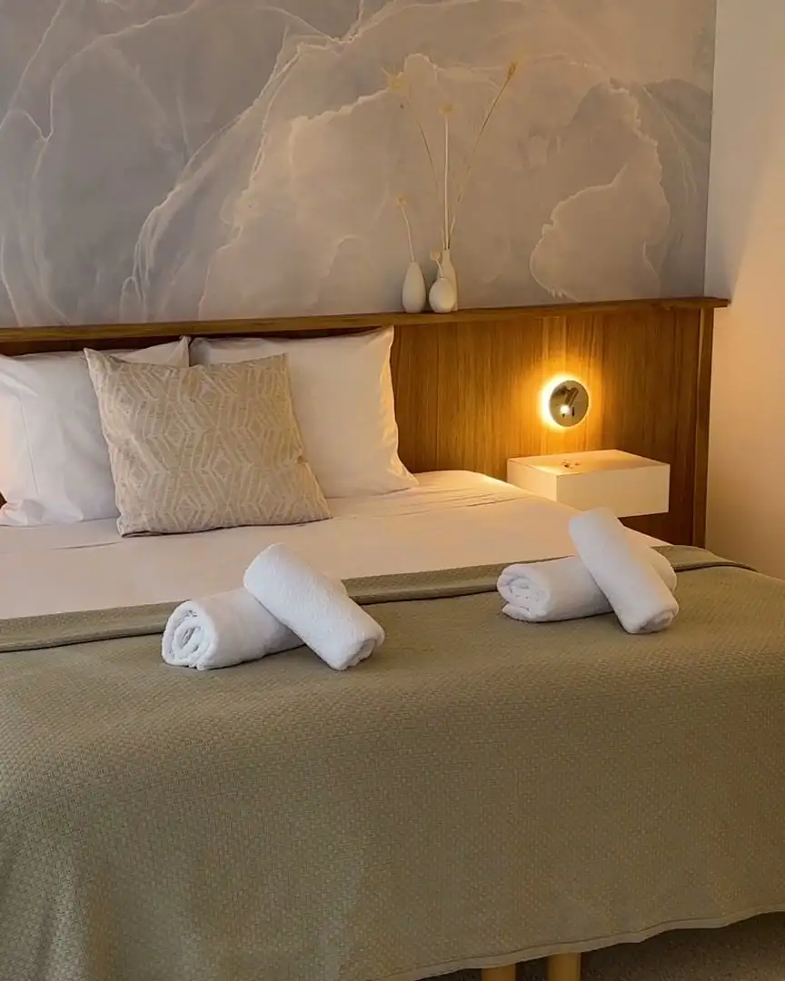 Chambre de la Villa Halo : lit fait, serviettes roulées, lampes de chevet allumées