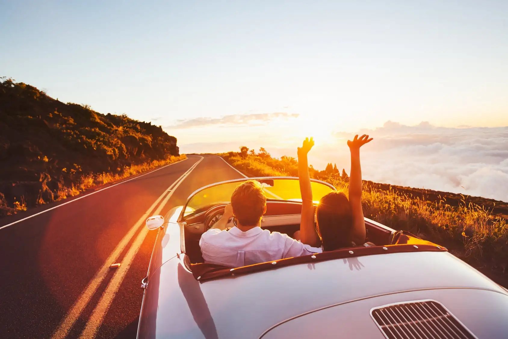 Couple en cabriolet de collection sur une route de crête au coucher du soleil
